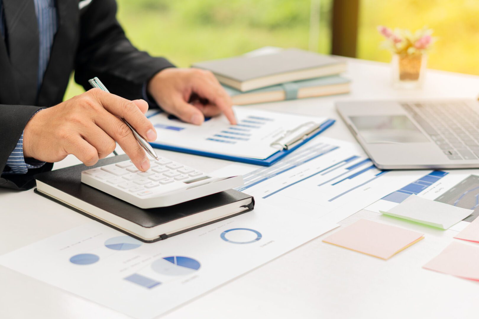 Businessman using calculator and analyzing charts.