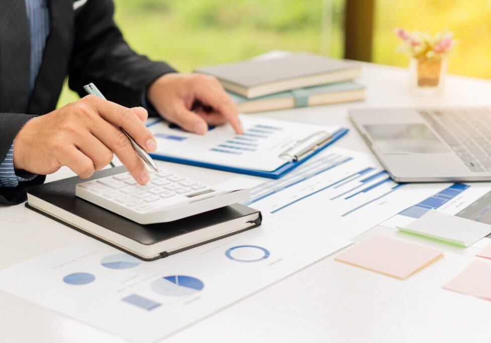 Businessman using calculator and analyzing charts.